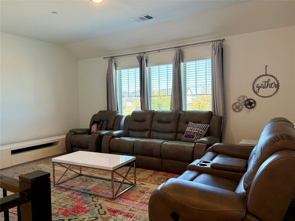 Vaulted ceiling room featuring a triple-window configuration with horizontal blinds and a built-in low-profile media console