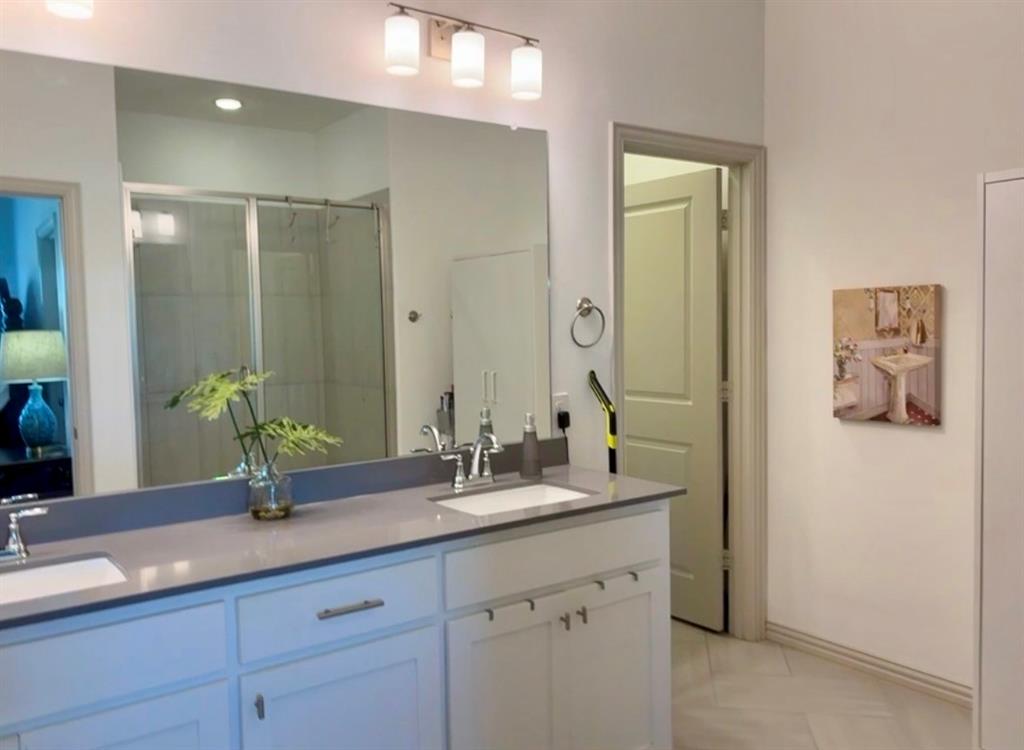 Dual-sink vanity with a solid-surface countertop, full-width mirror, and three-light wall-mounted fixture