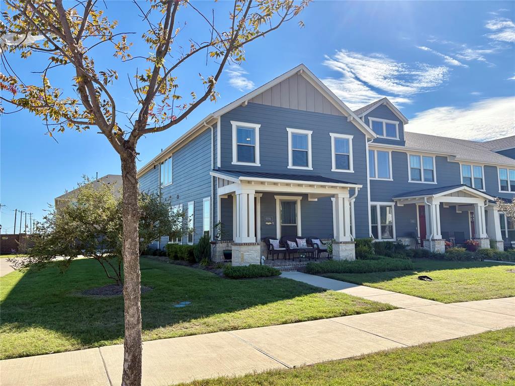 Multi-story blue horizontal siding exterior featuring a covered front porch, stone base columns, vertical siding accents, and a concrete walkway