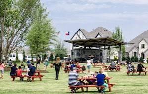 Outdoor community space featuring a covered amphitheater, stone facade, and expansive lawn area