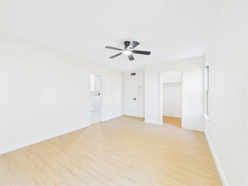 Room featuring wood-finish flooring, a matte black ceiling fan, and white-painted walls