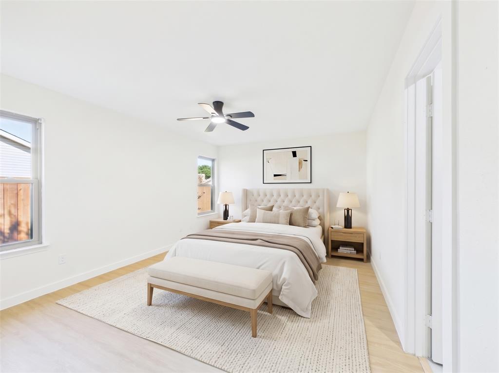 Neutral interior space featuring wood-finish flooring, dual-pane windows, and a ceiling-mounted light fixture with fan