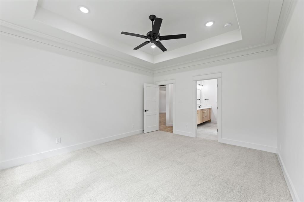 Unfurnished bedroom with a raised ceiling, baseboards, and light colored carpet