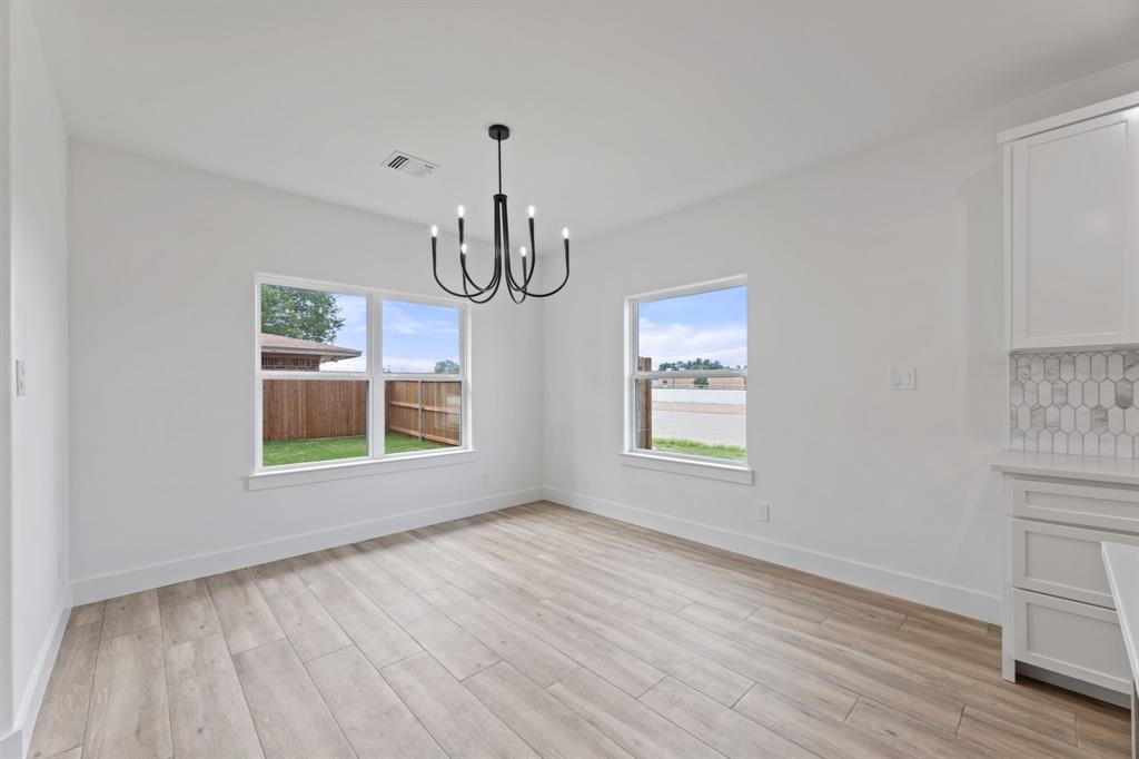 Unfurnished dining area featuring baseboards, visible vents, light wood-style floors, and a chandelier