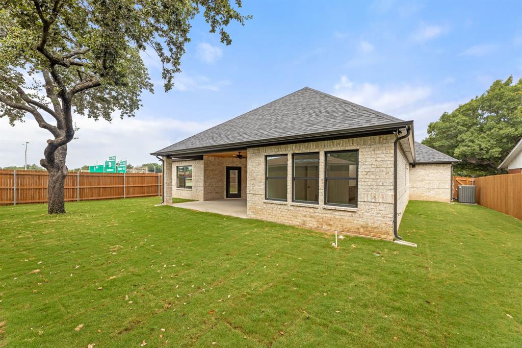 Back of property with a lawn, a shingled roof, a fenced backyard, and a patio area