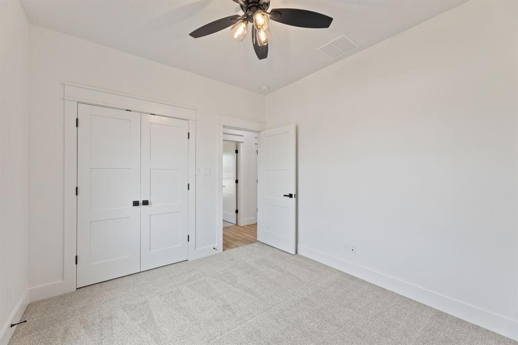 Unfurnished bedroom featuring a closet, carpet floors, baseboards, visible vents, and ceiling fan