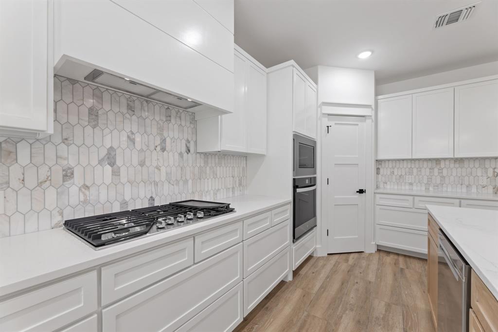 Kitchen featuring visible vents, premium range hood, white cabinetry, and stainless steel appliances