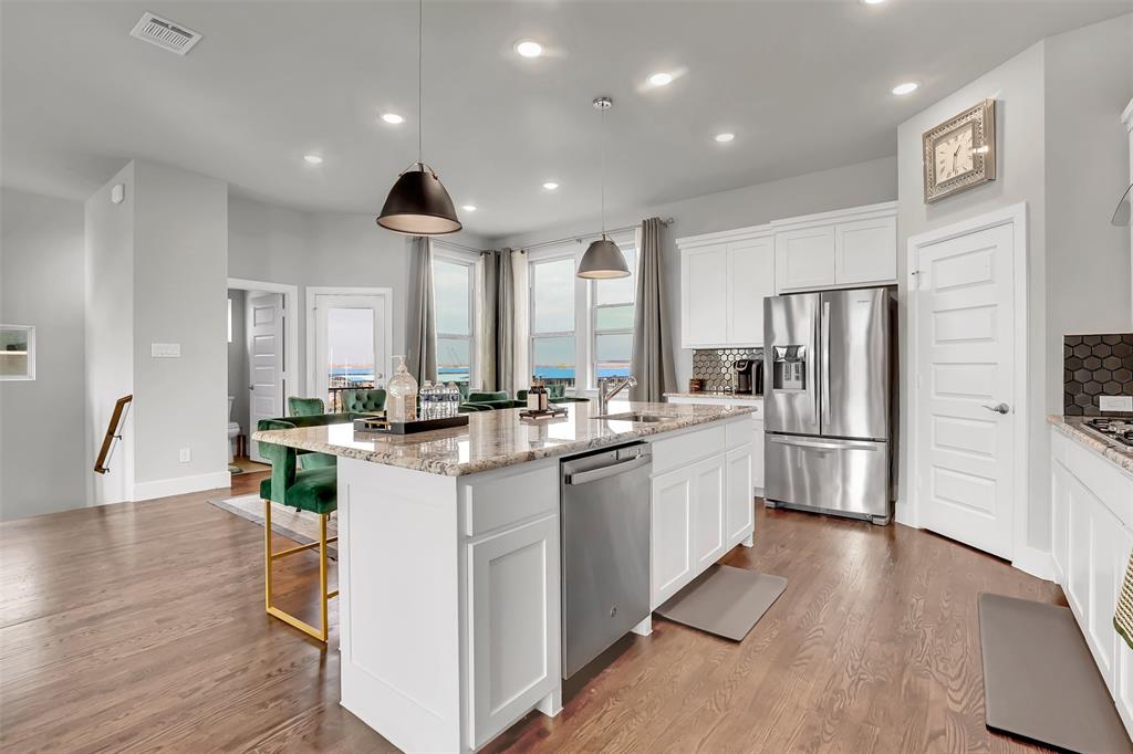 Kitchen featuring stainless steel appliances, white cabinets, tasteful backsplash, light stone counters, and a kitchen island with sink Kitchen featuring stainless steel appliances, white cabinets, tasteful backsplash, light stone counters, and a kitchen island with sink