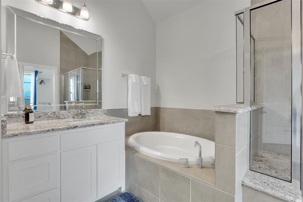 Full bath featuring vanity, a garden tub, a shower stall, and vaulted ceiling