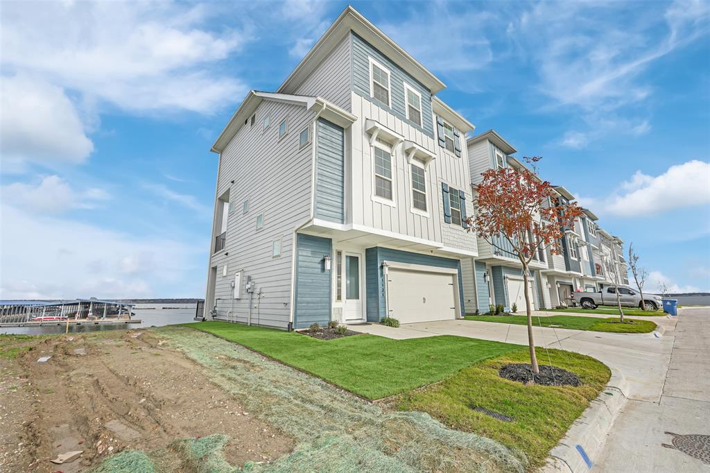 View of front of property with board and batten siding, concrete driveway, an attached garage, and a front lawn View of front of property with board and batten siding, concrete driveway, an attached garage, and a front lawn