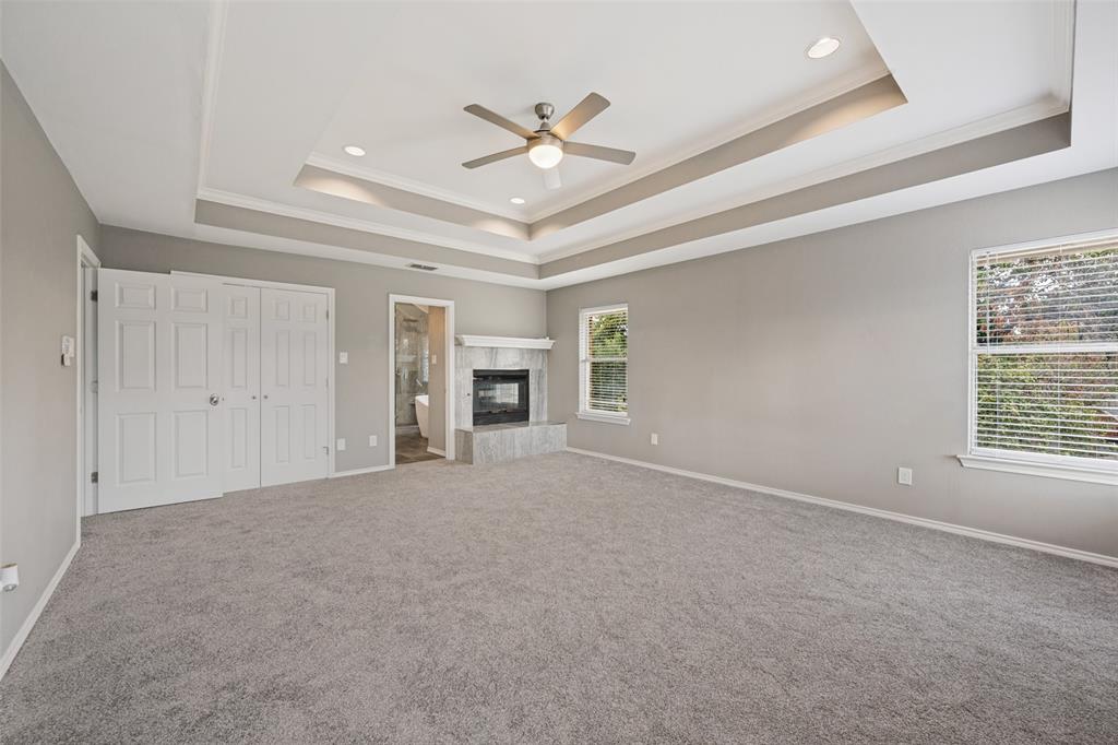 There is ample area near the fireplace for a sitting area in this primary bedroom.