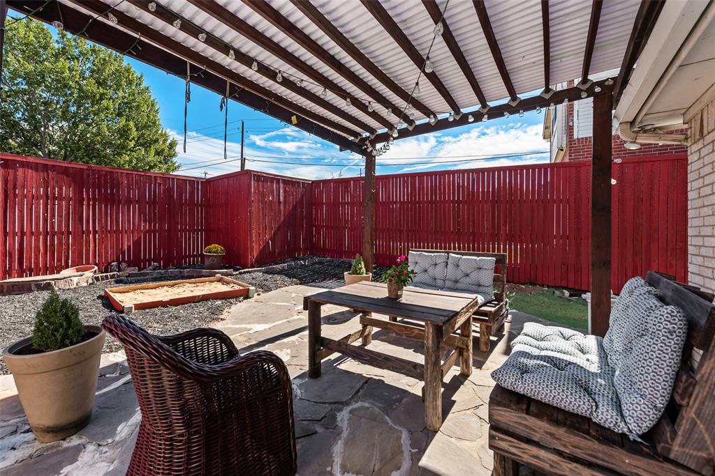 Outdoor living space featuring a flagstone patio, wood-framed pergola, and privacy fencing