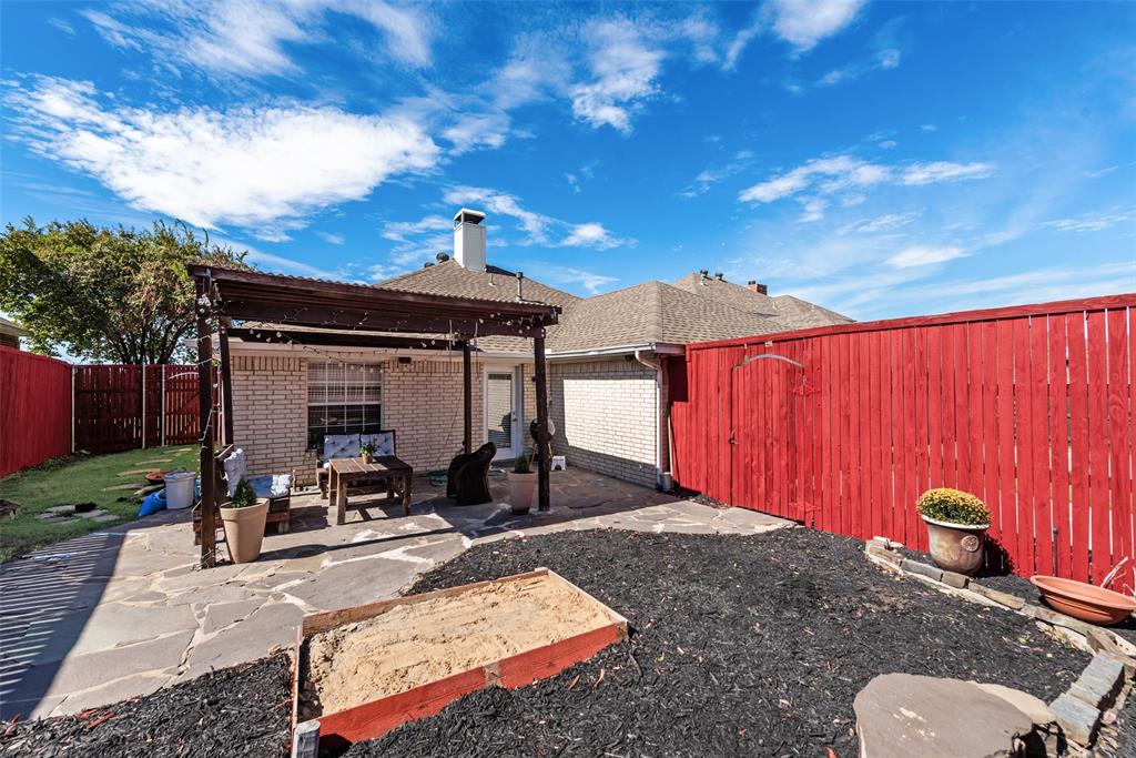 Backyard featuring a flagstone patio, wood-frame pergola, exterior brick cladding, and privacy fencing
