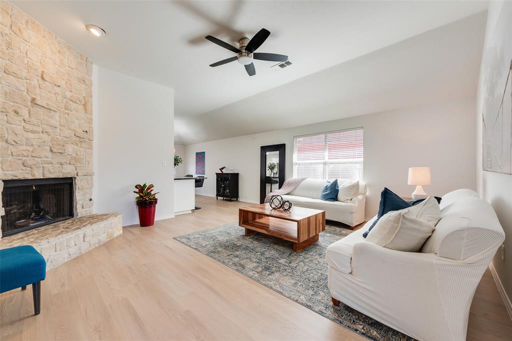 Stone-clad fireplace with a raised hearth, wood-finish flooring, vaulted ceiling, and ceiling fan Stone-clad fireplace with a raised hearth, wood-finish flooring, vaulted ceiling, and ceiling fan