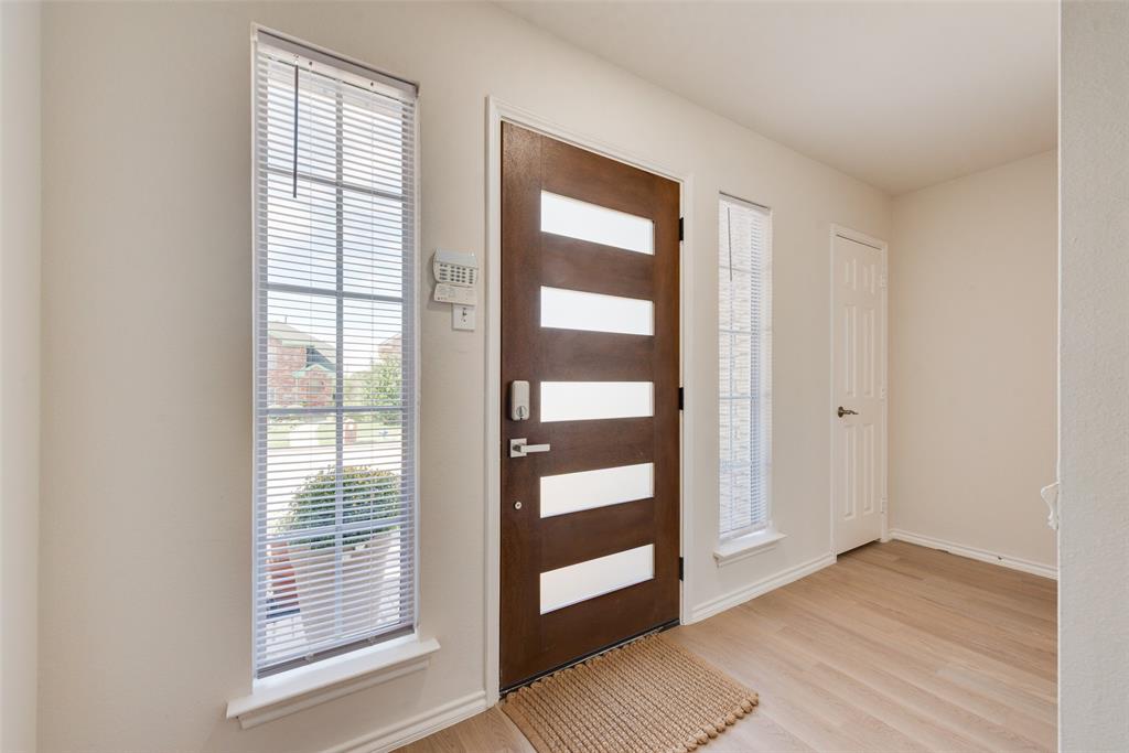 Entryway featuring a wood-finish door with horizontal glass panels, flanked by two tall windows, wood-finish flooring, and a six-panel door Entryway featuring a wood-finish door with horizontal glass panels, flanked by two tall windows, wood-finish flooring, and a six-panel door