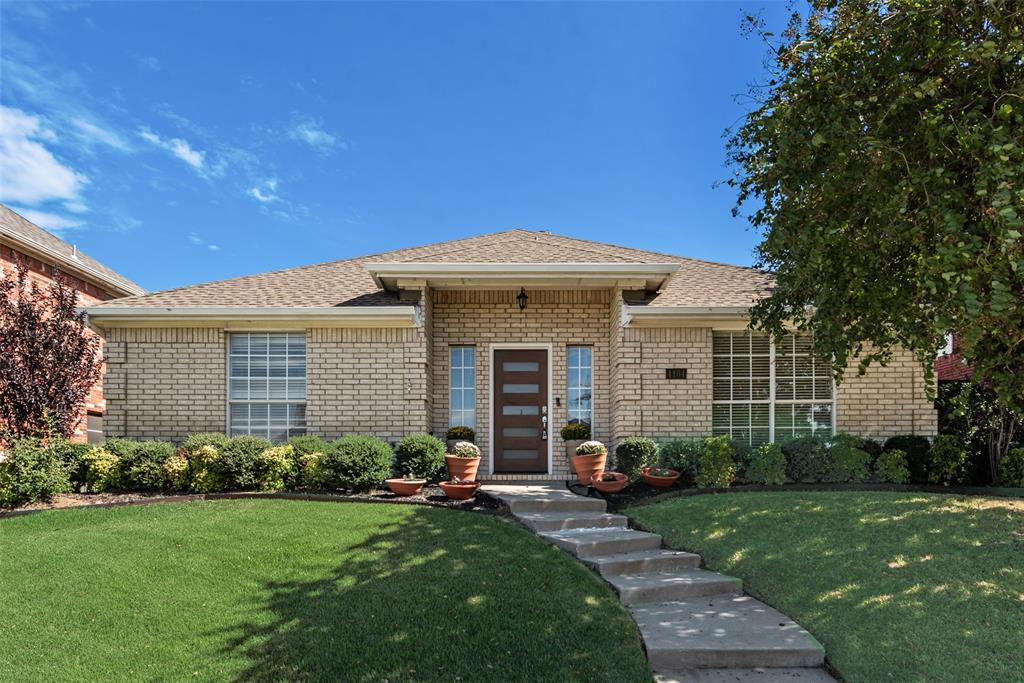 Single-story exterior featuring light brick masonry, a hipped roof, grid-pattern windows, and a modern front door with horizontal glass panels Single-story exterior featuring light brick masonry, a hipped roof, grid-pattern windows, and a modern front door with horizontal glass panels