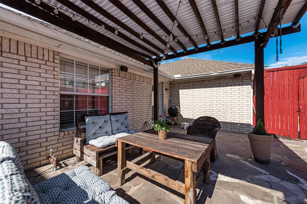 Covered patio featuring a wood pergola, brick exterior siding, and flagstone paving