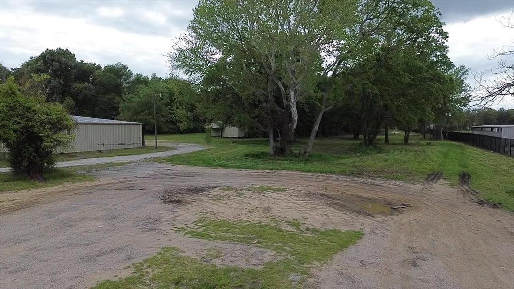 Expansive level lot featuring a metal-sided outbuilding, a gravel driveway, and mature trees Expansive level lot featuring a metal-sided outbuilding, a gravel driveway, and mature trees