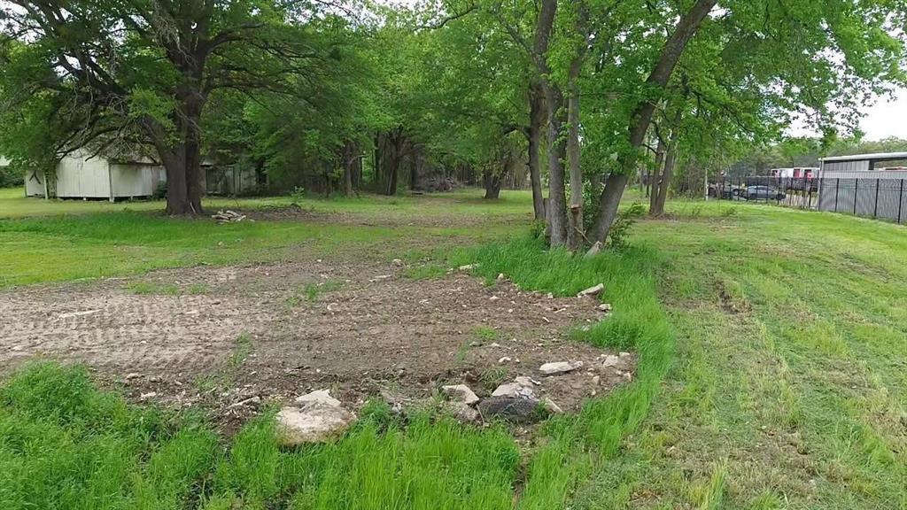 Expansive lot featuring mature trees, natural terrain, and a chain-link perimeter fence