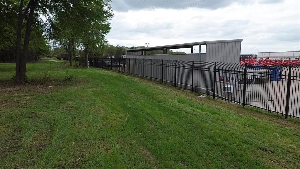 Level green space featuring established trees and perimeter metal fencing