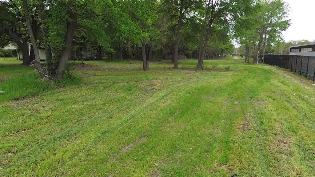 Expansive lot featuring mature trees, natural terrain, and perimeter metal fencing