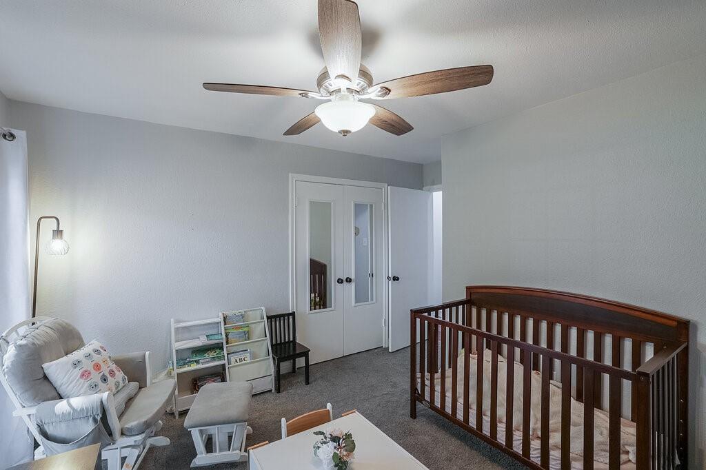 Room featuring neutral-toned walls, carpeting, a ceiling fan with integrated lighting, and dual-panel closet doors with inset mirrors