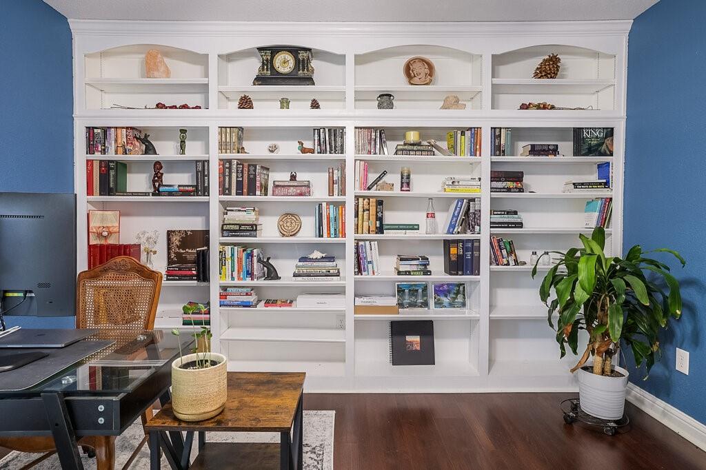 Floor-to-ceiling custom built-in white shelving featuring arched upper detailing and dark wood-finish flooring