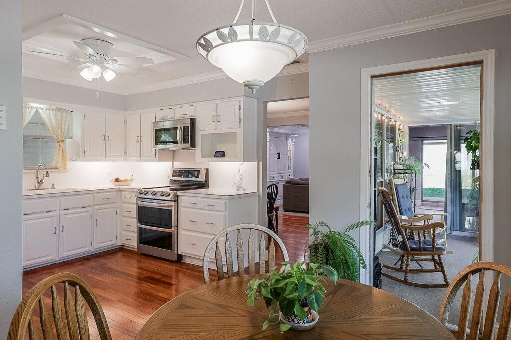 Kitchen featuring white cabinetry, stainless steel appliances, wood-finish flooring, recessed ceiling lighting, and a pendant light fixture
