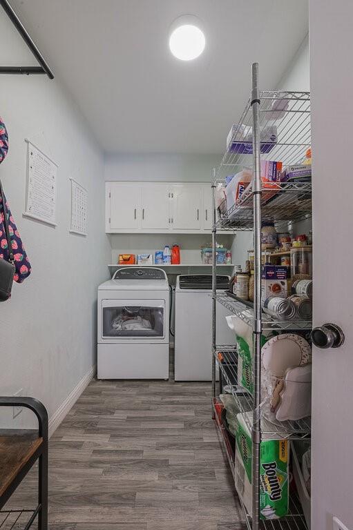 Laundry room featuring wood-finish flooring, white overhead cabinetry, an open shelving unit, and a flush-mount ceiling light