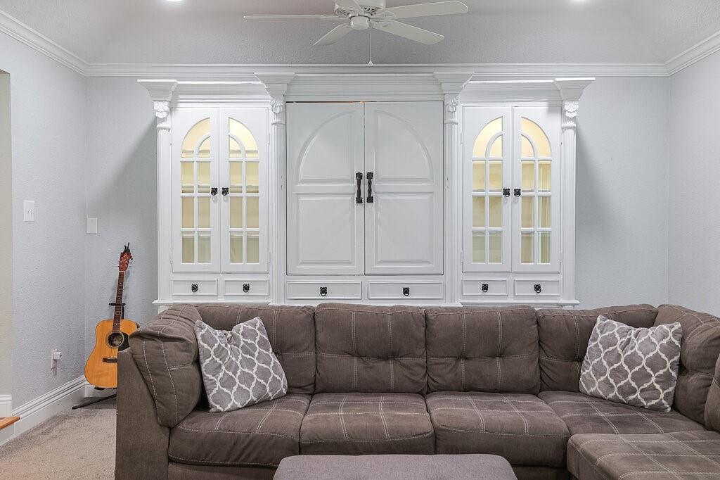 Custom white built-in cabinetry featuring arched glass-paneled display shelves, central storage, drawer detailing, and crown molding