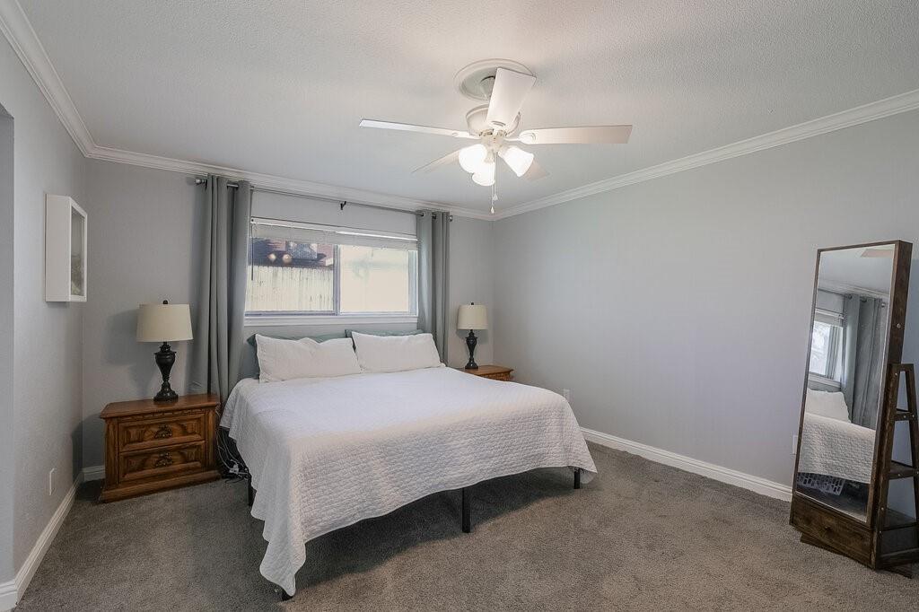 Bedroom featuring neutral wall paint, crown molding, wall-to-wall carpeting, and a ceiling fan with integrated lighting