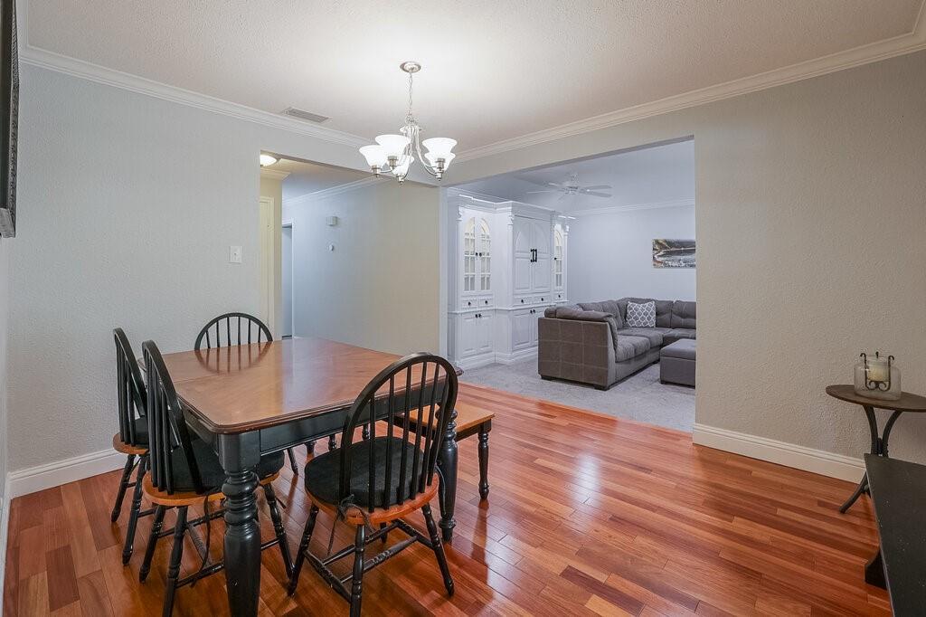 Wood-finish flooring, crown molding, multi-arm chandelier, and built-in floor-to-ceiling cabinetry