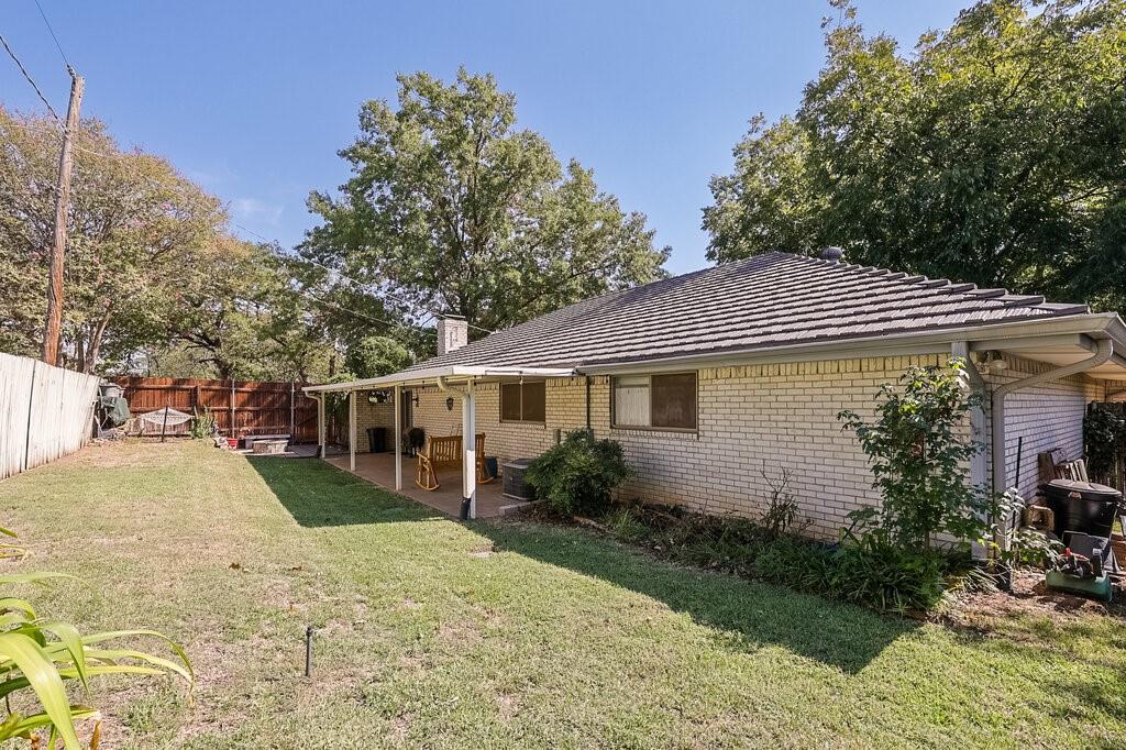 Brick exterior residence featuring a covered patio, a hipped roof with tile shingles, and a fenced backyard