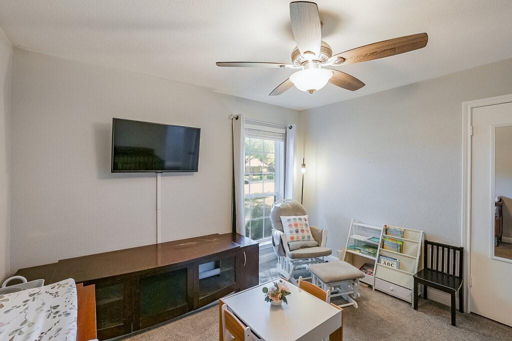 Neutral-toned interior featuring carpeted flooring, a ceiling fan with integrated lighting, and a window with horizontal blinds