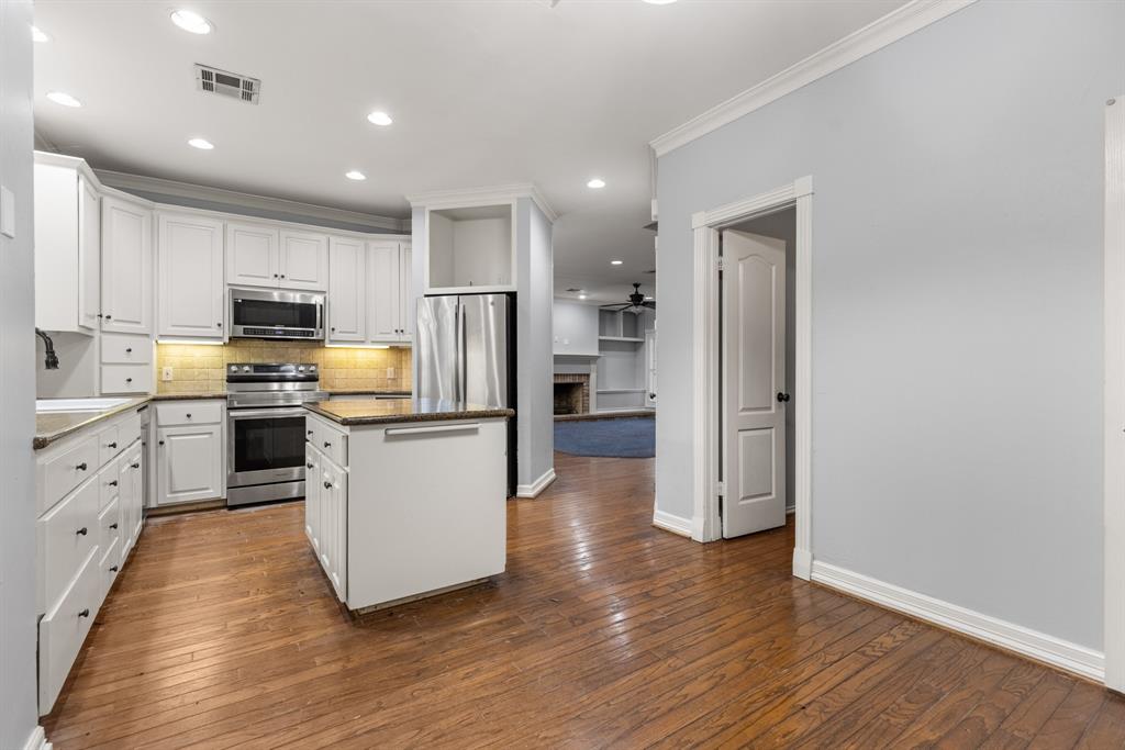 Kitchen featuring white cabinetry, wood-finish flooring, a central island, recessed lighting, and stainless steel appliances