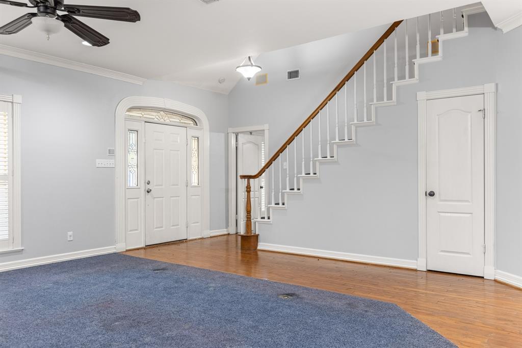 Foyer featuring wood-finish flooring, a staircase with a wooden handrail, and an arched entry door with side windows and a transom
