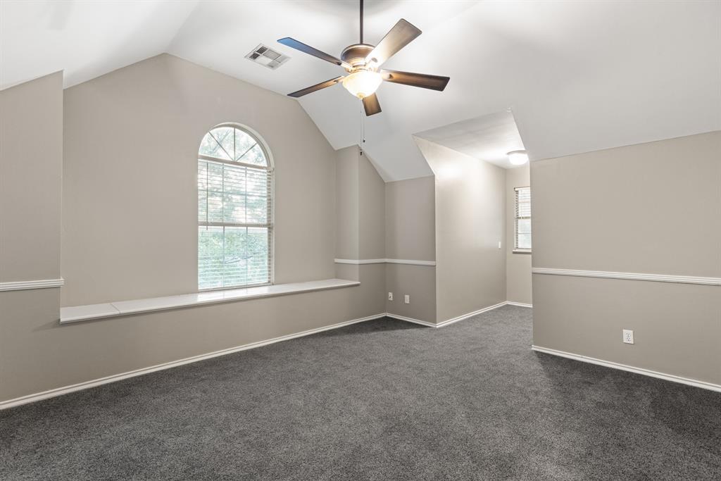 Vaulted ceilings featuring an arched window, a built-in window seat, chair rail molding, and a ceiling fan