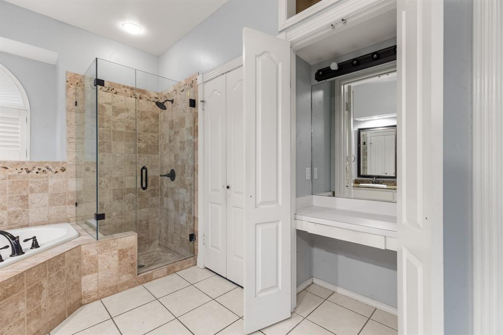Bathroom featuring a tiled shower with a glass enclosure, an integrated soaking tub, built-in vanity, and ceramic tile flooring