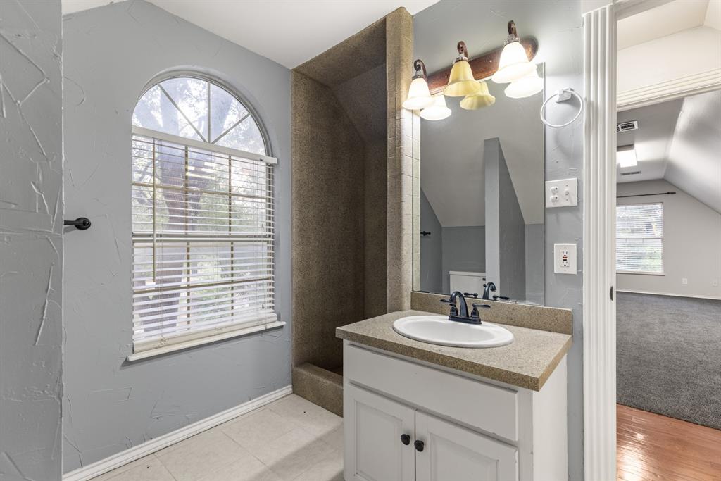 Bathroom featuring a vanity with a solid-surface countertop, an integrated oval sink, a wall-mounted light fixture, and an arched window