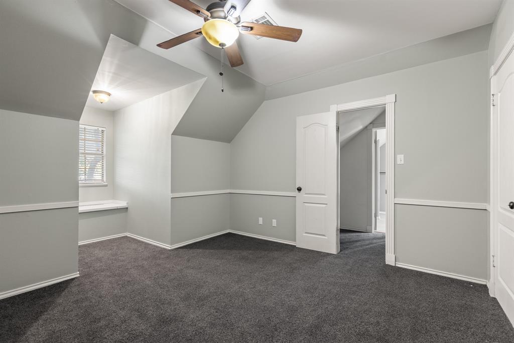 Room featuring vaulted ceilings, carpeted flooring, chair rail molding, built-in window seating, and a multi-blade ceiling fan with integrated lighting