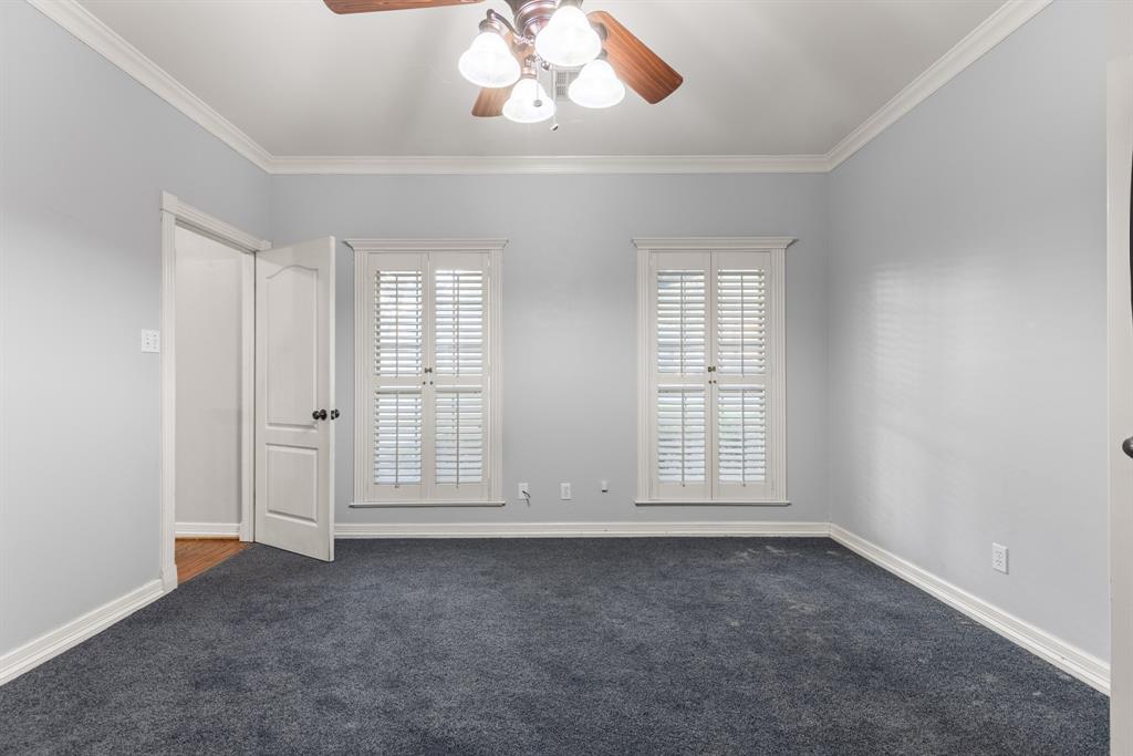Room featuring crown molding, neutral wall tones, plantation shutters, and a ceiling fan with integrated lighting
