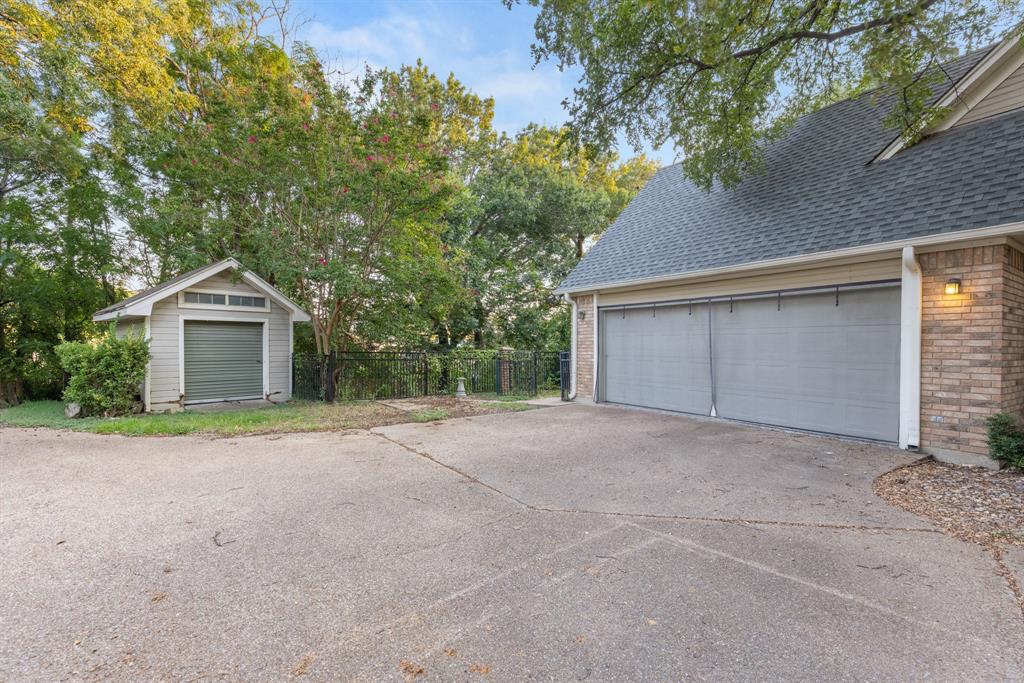 Attached two-car garage with brick and siding exterior, concrete driveway, and detached storage building featuring a roll-up door