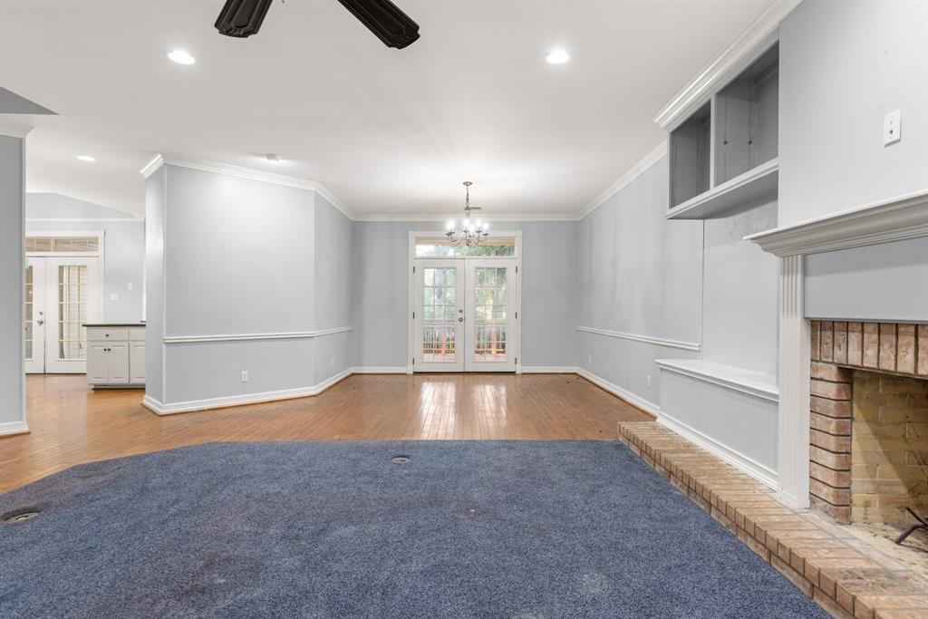 Living area featuring wood-finish flooring, a fireplace with a brick surround, built-in cabinetry, recessed lighting, and double glass pane doors