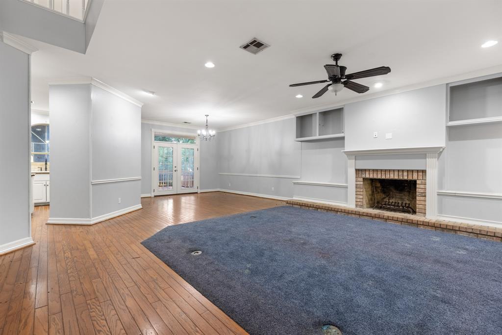 Living area featuring wood-finish flooring, recessed lighting, a ceiling fan, and a brick-surround fireplace with built-in cabinetry and shelving