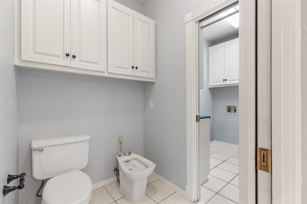 Bathroom featuring white cabinetry, ceramic tile flooring, a porcelain toilet, and a bidet