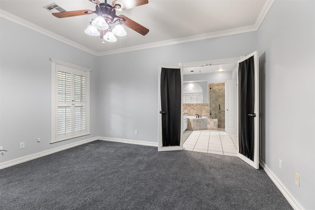 Carpeted room featuring white crown molding, shuttered windows, and a multi-light ceiling fan