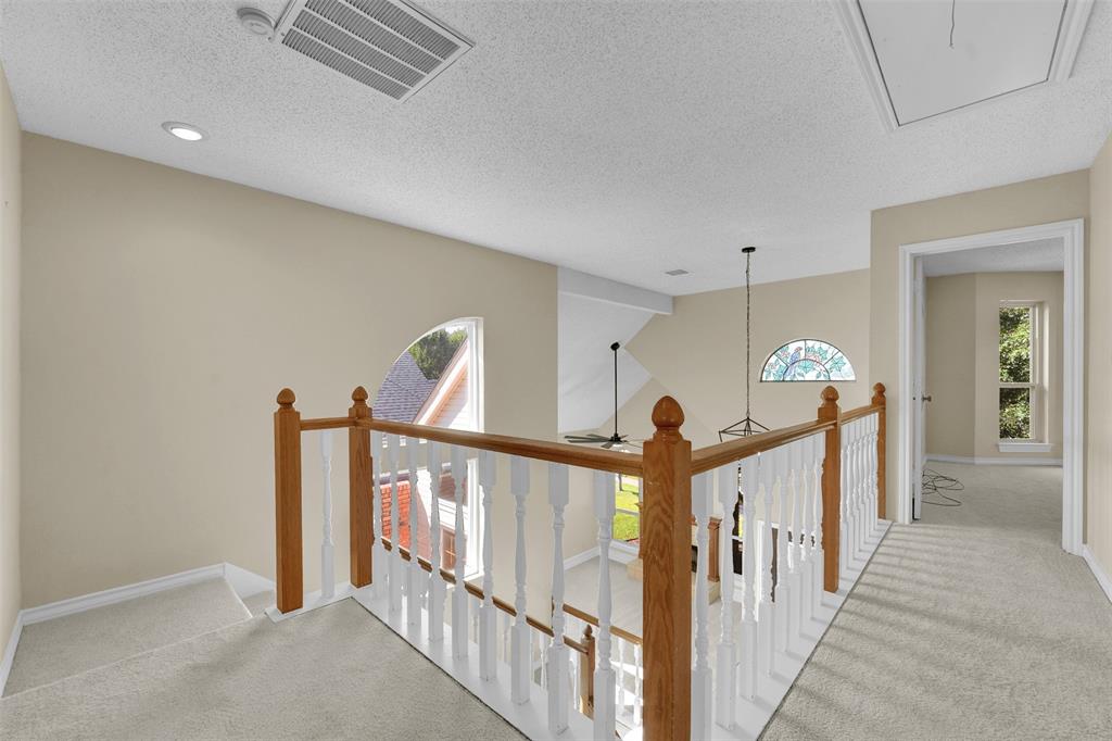 Wood-capped staircase railing with painted balusters, arched windows, and wall-to-wall carpeting