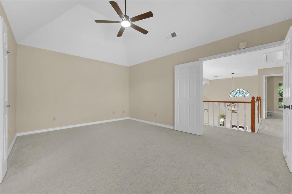 Vaulted ceilings, neutral carpeting, ceiling fan with integrated lighting, and multi-panel interior doors