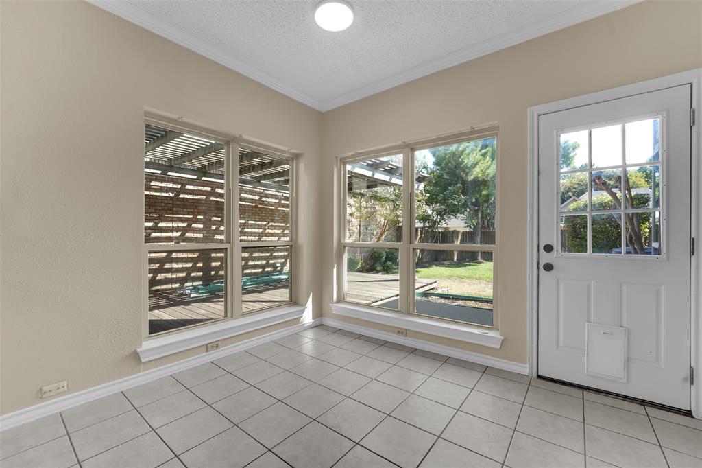 Sunroom featuring light-toned ceramic tile flooring, neutral walls, large windows, and a glass-paneled exterior door