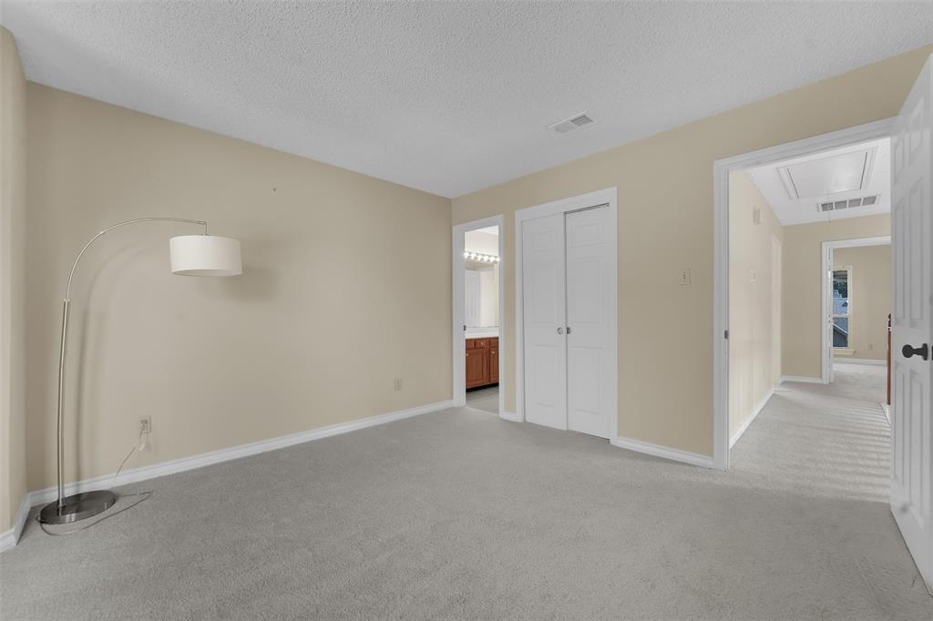 Neutral-toned bedroom featuring wall-to-wall carpeting, textured ceiling, and a dual-panel closet door